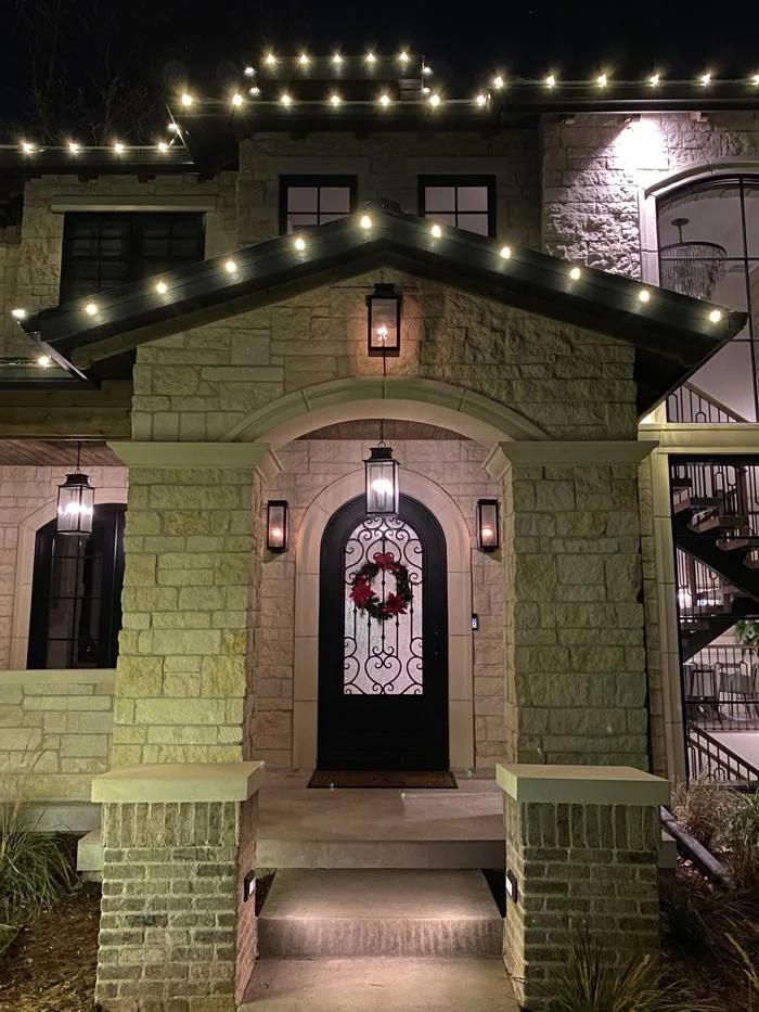 Warm-white lights along the front roofline of a Denver home